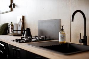 eine Küchentheke mit einer Spüle und einer Flasche Alkohol in der Unterkunft Michael the Tiny Cabin in Esperance in Doombup