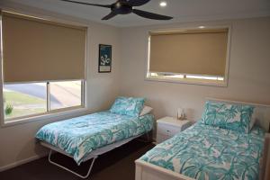 a bedroom with two beds and a ceiling fan at Amberlee House - bring your own linen in South West Rocks