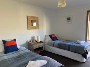 a bedroom with two beds and a table with a mirror at Lazy Sails Port - Pets welcome inside WiFi in Robe