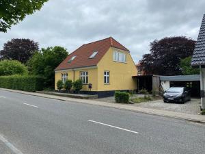 una casa amarilla con techo rojo en una calle en Jelling, en Jelling