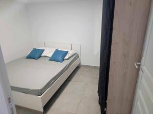a white bed with blue pillows in a room at F3 Maison au tampon in Le Tampon