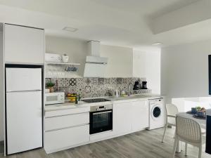 eine Küche mit weißen Geräten und einem Tisch mit Stühlen in der Unterkunft Casa Paraiso en Frigiliana in Frigiliana