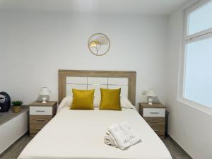 ein Schlafzimmer mit einem großen weißen Bett mit gelben Kissen in der Unterkunft Casa Paraiso en Frigiliana in Frigiliana