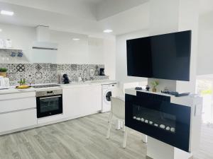 eine weiße Küche mit einem Flachbild-TV an der Wand in der Unterkunft Casa Paraiso en Frigiliana in Frigiliana + 46 Fotos