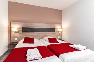 a bedroom with two beds with red and white sheets at Hotel Argos in Vendenheim