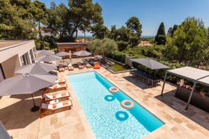 an outdoor swimming pool with umbrellas and chairs and a swimming pool at La Villa Monarque in Cap d'Agde