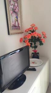 a desk with a computer monitor and a vase of flowers at Casa delle Rose in Fiumaretta di Ameglia