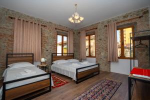 2 Betten in einem Zimmer mit Ziegelwänden und Fenstern in der Unterkunft InTown Guesthouse Shkoder in Shkodra