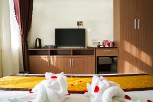 a hotel room with a bed and a flat screen tv at Bu Hotel Thành Phố Huế in Thôn Lại Thê