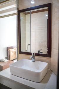 a white sink in a bathroom with a mirror at Bu Hotel Thành Phố Huế in Thôn Lại Thê