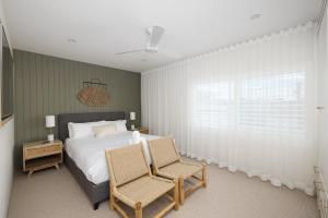 a bedroom with a bed and two chairs at 6 Shoal Edge in Shoal Bay