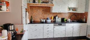 a kitchen with white cabinets and a black counter top at Chambre dans maison individuelle avec rez-de-chaussée partagé - cuisine, salle, salon et salle de bains in Saint-Brieuc