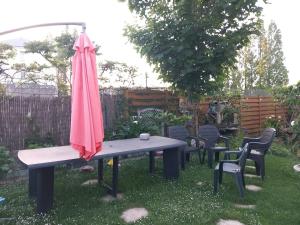 a picnic table with a pink umbrella and chairs at Chambre dans maison individuelle avec rez-de-chaussée partagé - cuisine, salle, salon et salle de bains in Saint-Brieuc