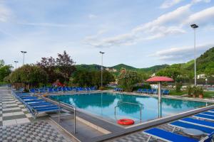 duży basen z niebieskimi krzesłami i parasolem w obiekcie Hotel Petrarca Terme w mieście Montegrotto Terme