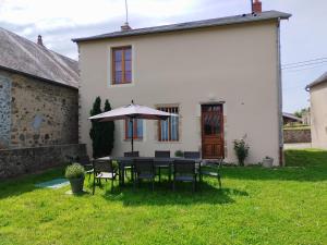 a table and chairs with an umbrella in front of a house at Le gîte de la poste in Onlay