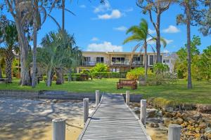 a wooden boardwalk leading to a building with palm trees at H2O Holiday Apartments - Unit 10 in North Haven