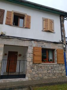 a building with wooden shutters and a window at VIVEIRO.CELEIRO. CASA TRANQUILA. RESURRECTION FEST in Cillero