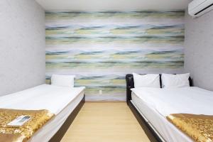 two beds in a room with a painting on the wall at 静響の宿 Silent Echo Inn in Osaka