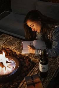 a woman sitting at a table with a book and a bottle of wine at Yox Hotel Boutique in San Crist&oacute;bal de Las Casas