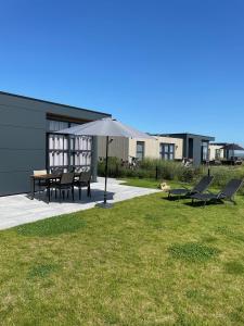 a patio with a table and chairs and an umbrella at Enkhuizer Strand Chalet Windrose mit Zaun Haus Nr 225 in Enkhuizen