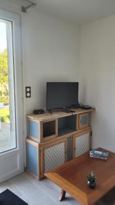 sala de estar con TV en un soporte de madera en Le Truc en plus, accessibles PMR, appartement 45 m2 mitoyen dans une maison avec un autre appartement, en Guérard