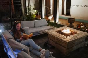 a woman sitting in a chair reading a book in front of a fireplace at Yox Hotel Boutique in San Crist&oacute;bal de Las Casas