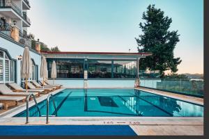 a swimming pool with chairs and a house at Aqua Princess Hotel in Kaş