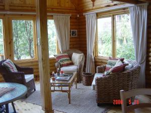 a living room with chairs and a table and windows at Log Villa in Cape Town
