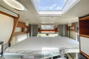 a bed in the middle of a room with a skylight at Autocaravana Baron 573 in Cerdanyola del Valles