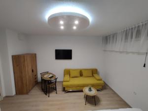 a living room with a yellow couch and a table at Apartmani Uroš Studio Trebinje in Trebinje