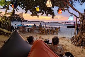 a group of people sitting in a hammock on the beach at Breizh Cape Beach Bungalows in Ko Lanta