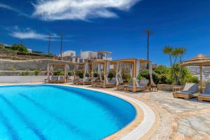 a swimming pool with lounge chairs and an umbrella at Marisso Hotel in Mikonos