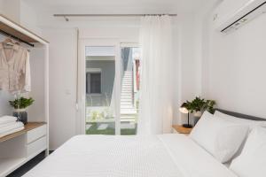 a white bedroom with a bed and a sliding glass door at Roxani Residential Complex in Ofrínion +54 photos
