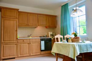 a kitchen with wooden cabinets and a table with a tablecloth at Ferienwohnung Adriaurlaub Sachsen in Großdubrau