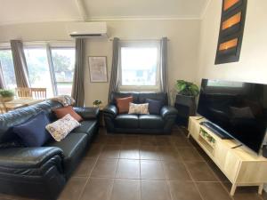 a living room with black leather furniture and a flat screen tv at Osprey Holiday Village Unit 113 2 Bedroom in Exmouth