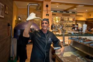 a man standing in a kitchen holding up a hat at Hotel la Palma au Lac in Locarno