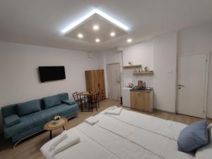 a living room with a blue couch and a kitchen at Apartmani Uroš Studio Trebinje in Trebinje