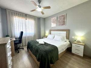 a bedroom with a bed with a desk and a ceiling fan at Beach Apartment, Torre Benagalbón in Torre de Benagalbón