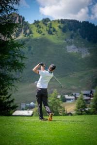 un hombre balanceando un palo de golf en un campo en Apartment Amore, en Riederalp