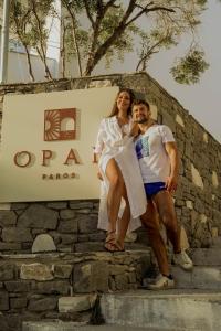 a man and a woman sitting on a stone wall at Opal Paros in Naousa