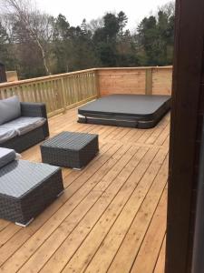 a wooden deck with a bed and couches on it at Ebba Lodge in Eyemouth +1 photo