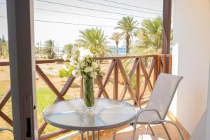 a glass table with a vase of flowers on a balcony at PATH Latchi Beachfront Apartments in Lachi