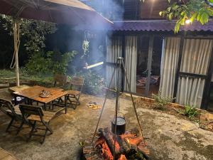 Yoga-Tea-Houses في Ấp Tân Hà: حفرة نار في الفناء الخلفي مع طاولة وكراسي