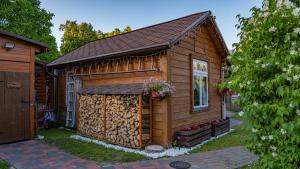 a small wooden cabin with a pile of fire wood at Strazdu Māja in Jūrmala