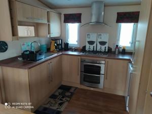a kitchen with wooden cabinets and a stove top oven at Mobil-home anglais 3 chambres in Pont-Aven +16 photos
