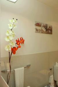 a bathroom with a vase with white and orange flowers at GuestReady - Rodamar Apartment in Ilhéu do Gorgulho +14 photos