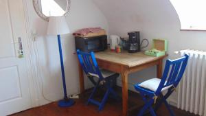 a table with two blue chairs and a lamp at Les Pommerets in Le Petit-Couronne