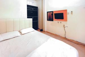 a bedroom with a bed and a tv on the wall at Amira House Kisaran RedPartner in Kisaran