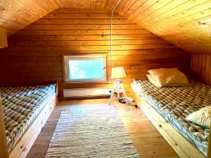 two beds in a wooden room with a window at Villa Venekoski in Jyväskylä