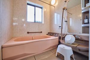 富士吉田市にあるAPROSTAY旭11のピンクの浴槽と白いスツールのあるバスルーム